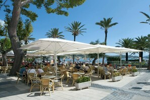 Outdoor seating with umbrellas, wicker chairs, and potted plants.