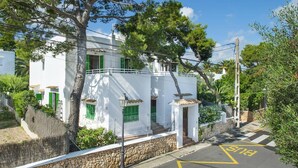 A white building with green shutters, a stone wall, and a clear blue sky. - Villa Malen by Villa Plus (Cala d'Or)