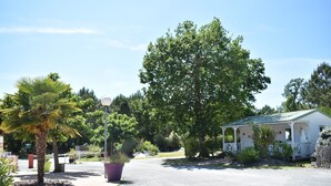 A small white building with a green roof, surrounded by trees and a paved driveway.