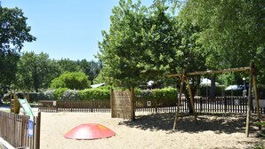 A sandy playground area with a swing set and a slide.
