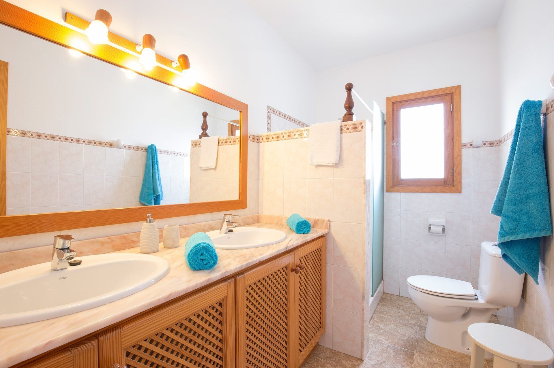 Ein Badezimmer mit zwei Waschbecken, einem Spiegel, einer Toilette und einem Fenster.