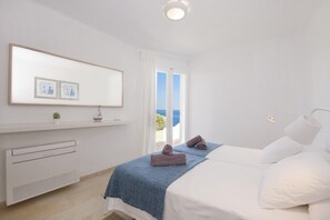 A bedroom with a bed, a bedside table, a mirror, and a view of the sea. - Villa S'Algar by Villa Plus (Felanitx)