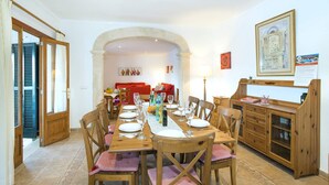 A dining area with a long wooden table set for four, surrounded by wooden chairs with pink cushions. - Villa Sol Pollensa by Villa Plus (Mallorca)