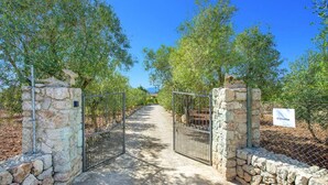 A stone gate leading into an olive grove with a clear sky. - Villa S'Olivellas by Villa Plus (Mallorca)