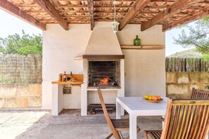 An outdoor kitchen with a brick oven, a table with fruits, and a hanging lantern.