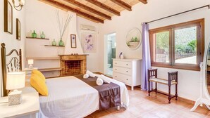 Una camera da letto con un letto, un comodino, una lampada e una finestra vista verde.
