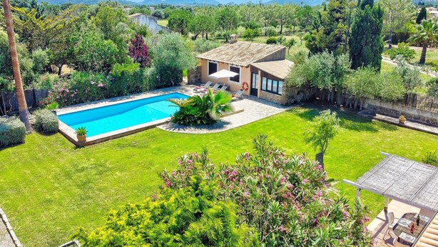 Una casa con piscina, circondata da vegetazione lussureggiante e un panorama montuoso.