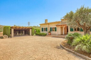 A Mediterranean-style villa with a paved courtyard, a covered pergola, and a well-maintained garden. - Villa Vidrier I by Villa Plus (El Vilà)