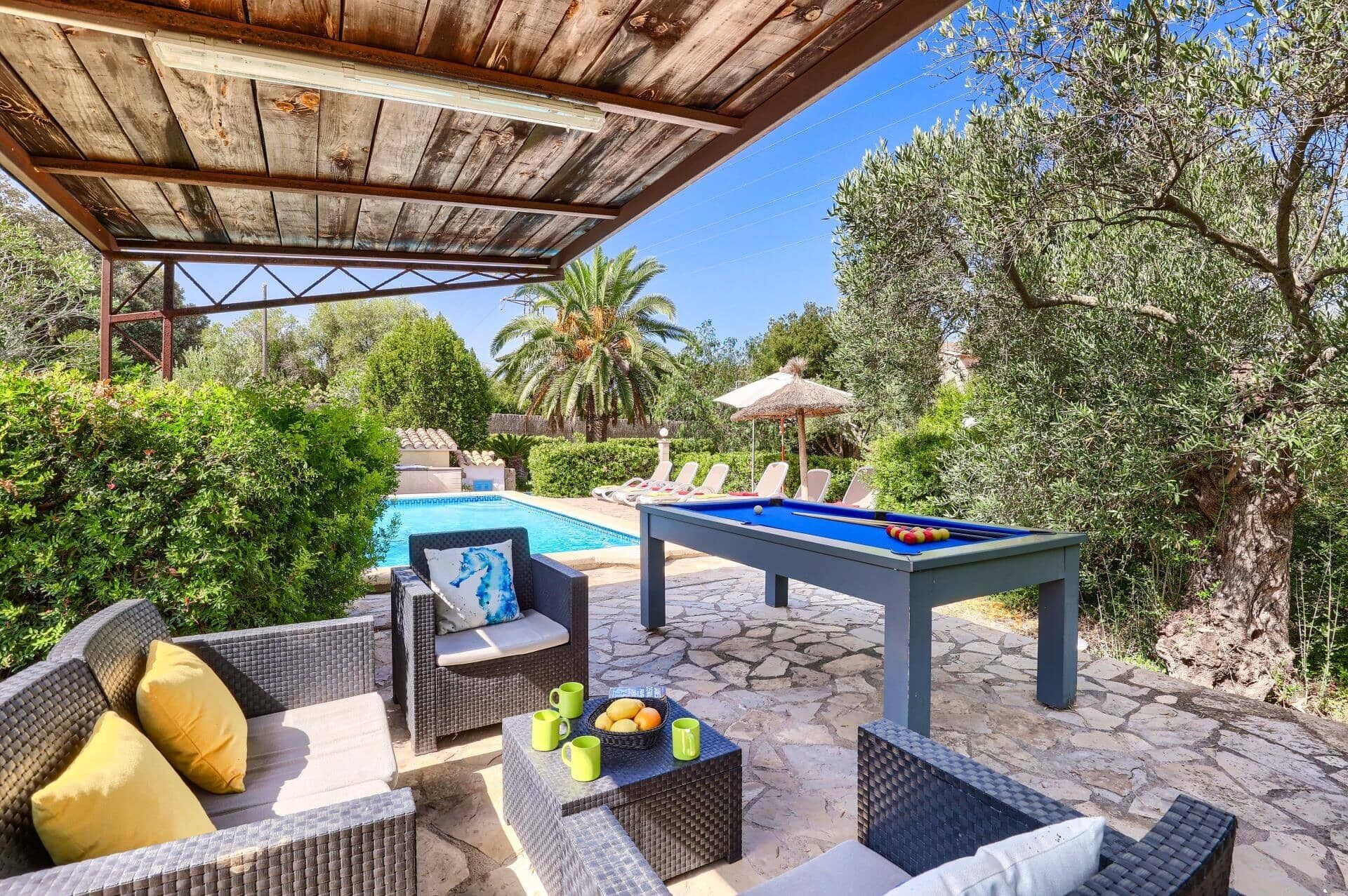 An outdoor pool area with lounge chairs, a pool table, and a covered seating area.