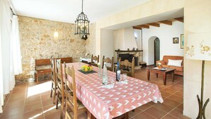 A dining area with a stone wall, wooden furniture, and a fireplace. - Villa Vidrier II by Villa Plus (El Vilà)