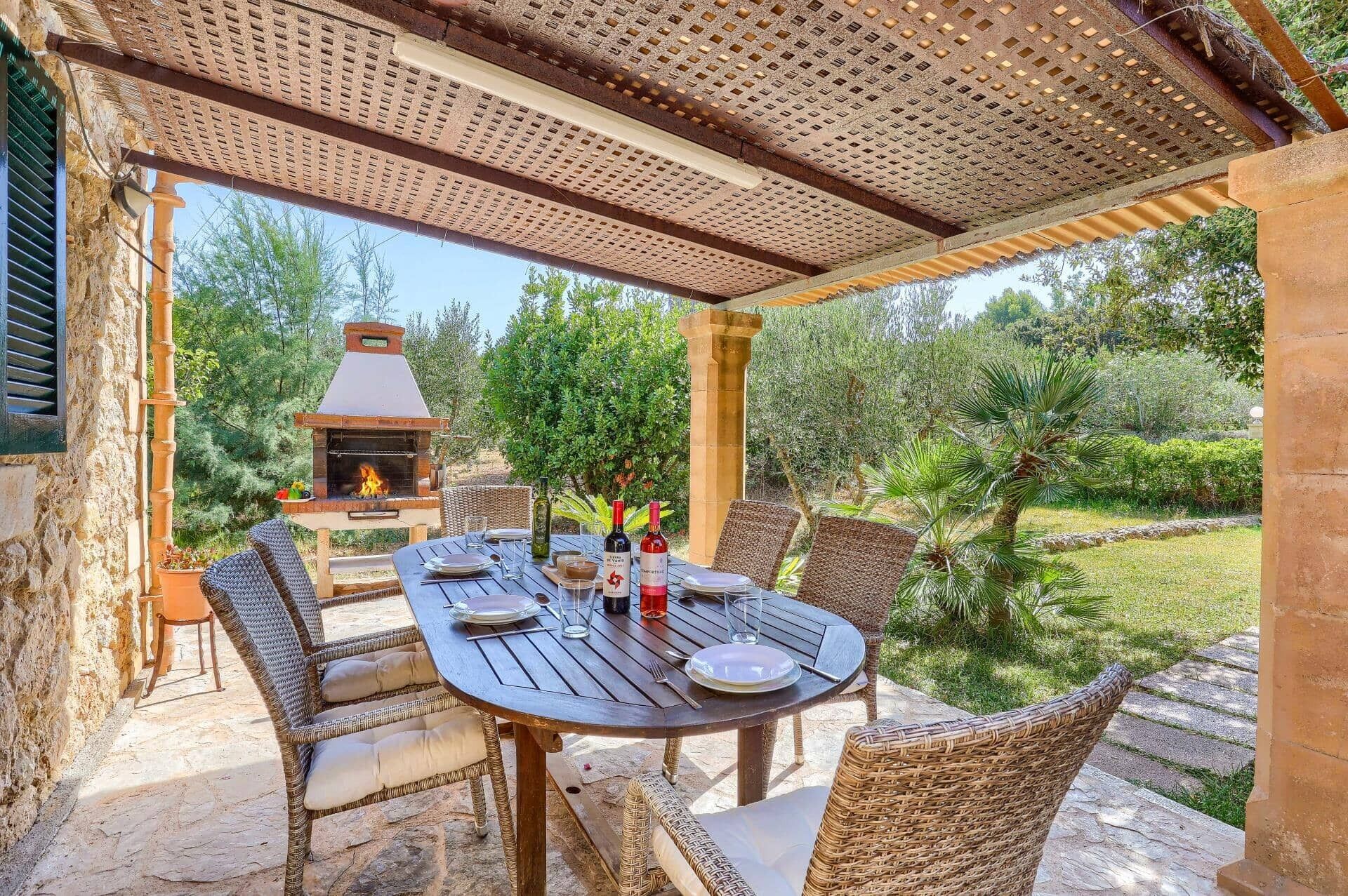 An outdoor patio with a round table, wicker chairs, and a stone floor.