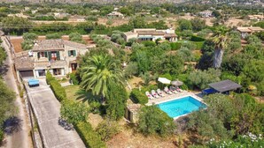 A residential area with a swimming pool, surrounded by greenery and houses.