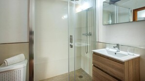A modern bathroom with a glass-enclosed shower, a wooden vanity, and a large mirror. - Villa Vidrier II by Villa Plus (El Vilà)