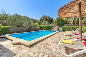 A swimming pool with a stone deck, surrounded by lounge chairs with towels, and a thatched umbrella. - Villa Vidrier II by Villa Plus (El Vilà)
