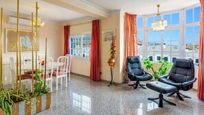 A room with a dining area, two black leather chairs, a table, a decorative plant, and a window with a view. - Villa Tia Ana by Villa Plus (Fuengirola)