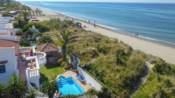 Une propriété résidentielle dotée d’une piscine, offrant une vue sur la plage et comprenant un jardin.