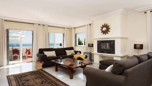 Un salon avec un canapé, une table basse, une cheminée et une vue sur l’océan.