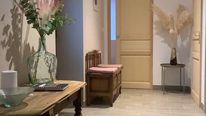 Ein Flur mit einem Holztisch, Stühlen, einer Pflanzvase und einer Tür.