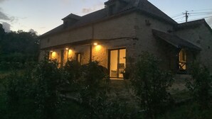 Ein rustikales Haus mit geneigtem Dach und einer Veranda mit Beleuchtung.