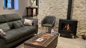 Ein gemütliches Wohnzimmer mit Steinwand, Kamin, Sofa und Couchtisch.