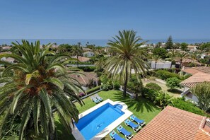 A pool area with a clear view of the sea, surrounded by palm trees and a residential neighborhood. - Villa Oasis Beach by Villa Plus (Marbella)