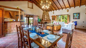 Une salle à manger spacieuse avec un haut plafond en bois, une cheminée en pierre et une vue sur l’extérieur.