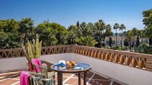 A balcony with wicker furniture, a table with a fruit bowl, and a cactus plant.