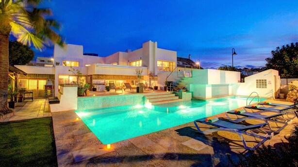 A modern multi-story house with a swimming pool and outdoor seating area.