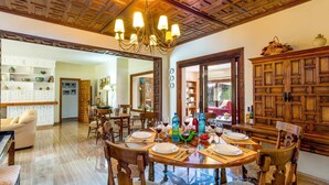 A dining area with a wooden ceiling, a chandelier, and a dining table set for six. - Villa Ramos by Villa Plus (Atalaya Isdabe)