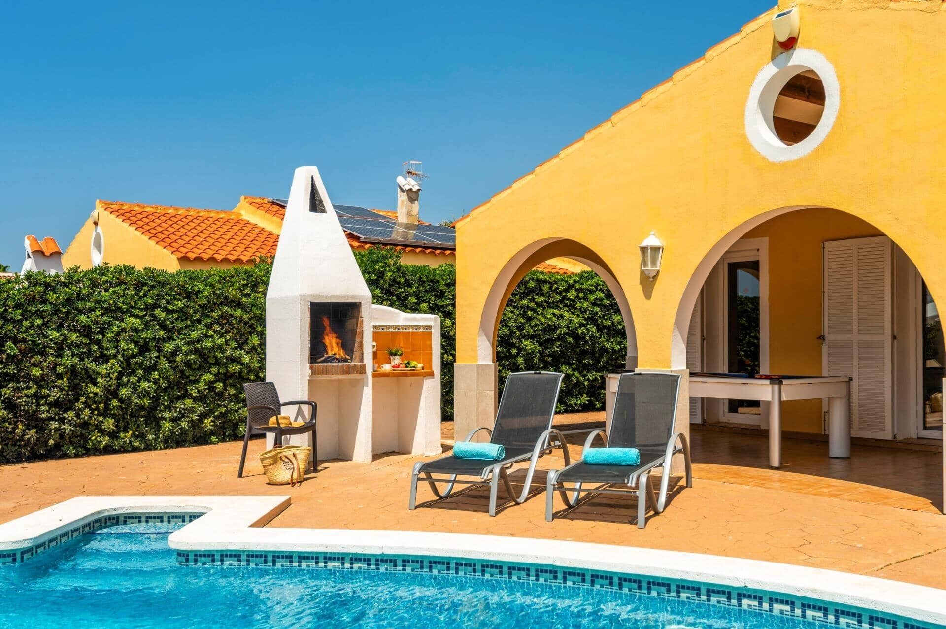 Un espace aménagé au bord de la piscine, avec des chaises longues, un barbecue et une petite table.