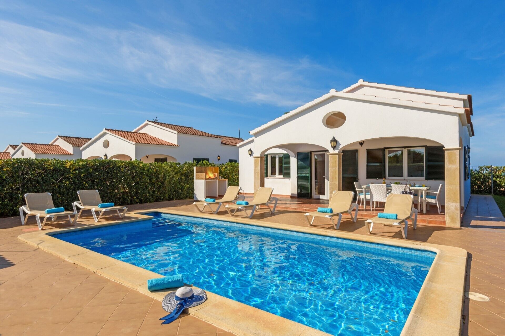 Ein Poolbereich mit Liegestühlen und einer überdachten Terrasse.