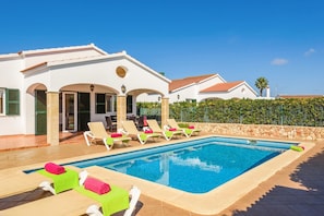 Un área junto a la piscina con sillones de descanso y una alberca.