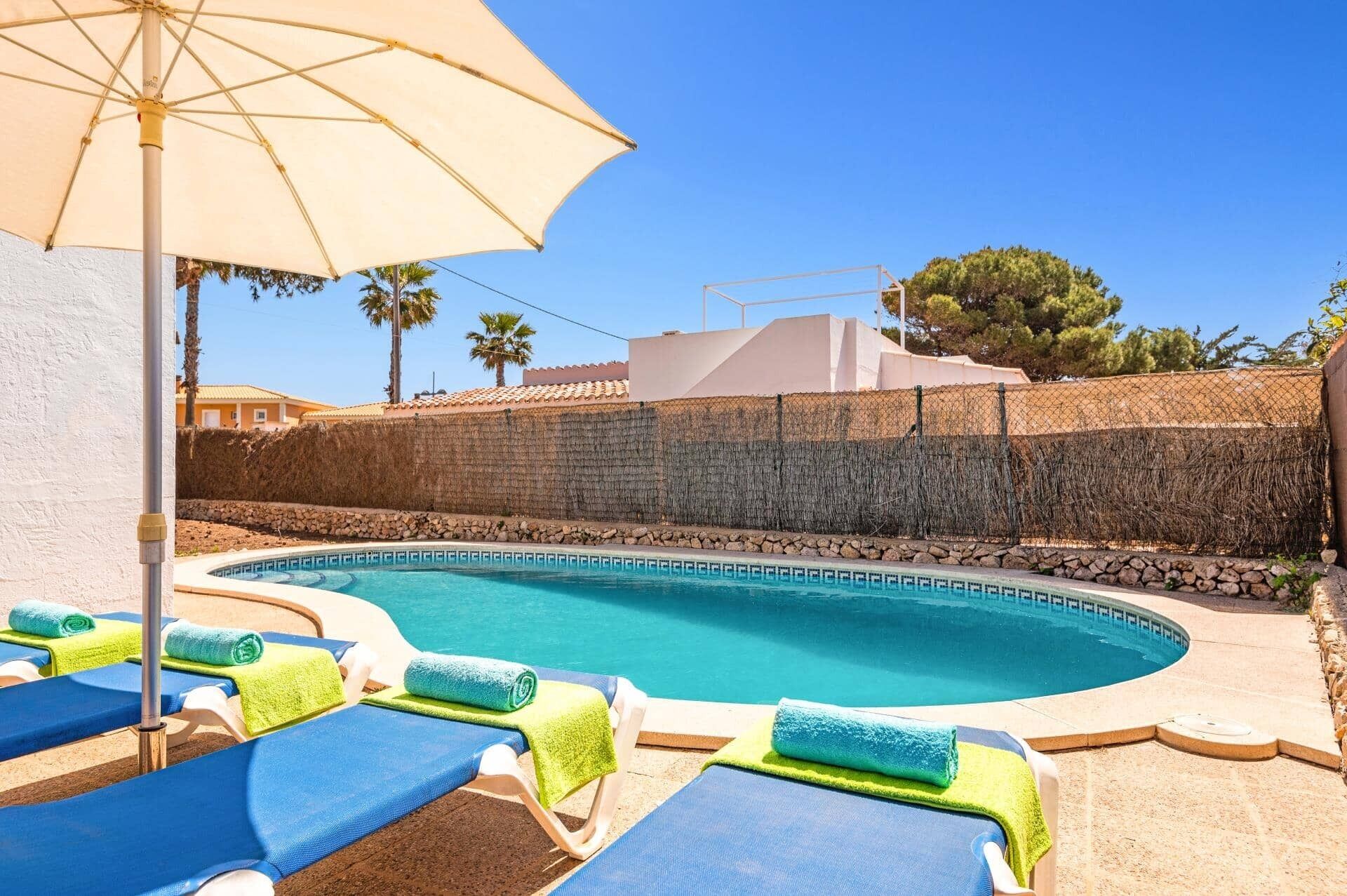 Ein Poolbereich mit Liegestühlen und Sonnenschirm.