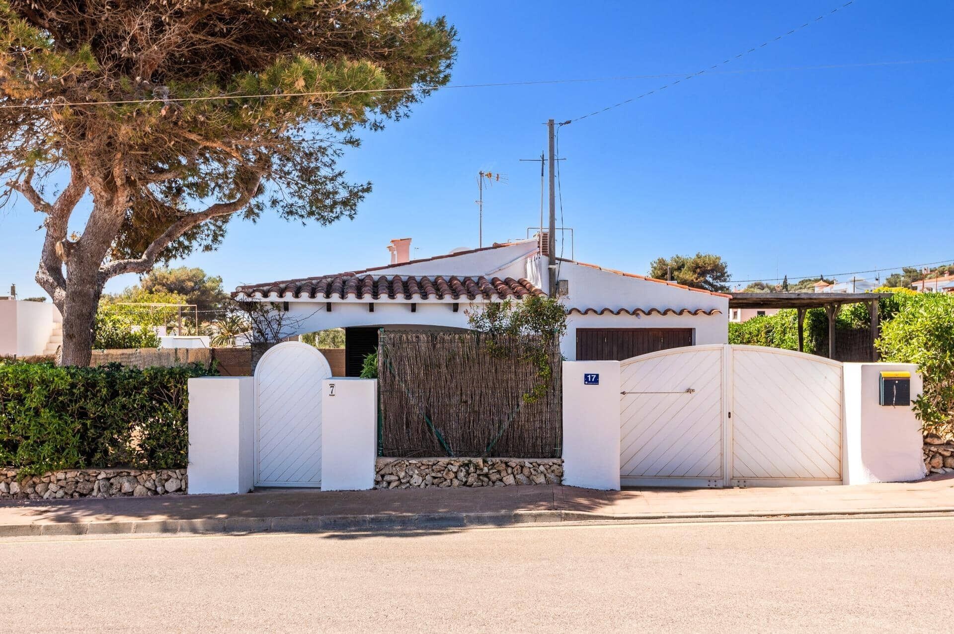A residential property with a white exterior, a tiled roof, and a gated entrance.