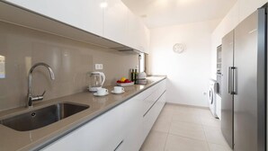 Eine moderne Küche mit Spülbecken aus Edelstahl, einem Wasserkocher, einem Toaster und einem Kühlschrank.