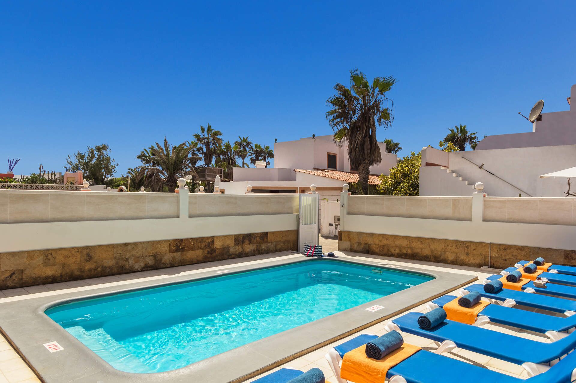 A swimming pool with lounge chairs and a gate.