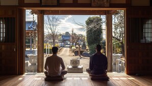 Two individuals seated in meditation, facing an outdoor garden with traditional architecture. - TEMPLESTAY ZENSO (Chiyoda Town, Oura District)