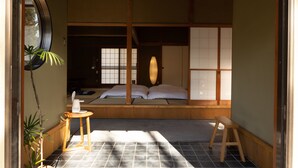 A traditional Japanese room with tatami flooring, a low wooden bed, a small stool, and a potted plant. - TEMPLESTAY ZENSO (Chiyoda Town, Oura District)