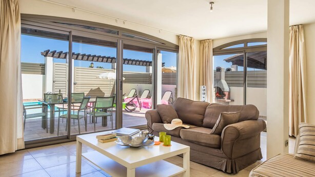 A spacious living area with a sliding glass door leading to an outdoor patio. - Villa Pino by Villa Plus (Corralejo)
