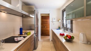 A modern kitchen with stainless steel appliances, a wooden door, and a window. - Villa Pino by Villa Plus (Corralejo)
