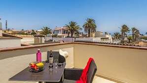 Ein Balkon mit einem Tisch für zwei Personen, einer Weinflasche und einer Obstschale.