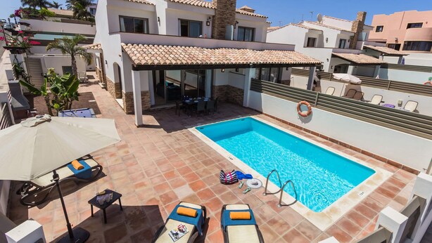 A rooftop pool area with lounge chairs, a covered seating area, and a swimming pool. - Villa Jenny by Villa Plus (Corralejo)