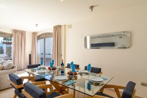 A modern dining area with a glass table, blue napkins, and a mirror on the wall.