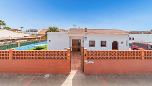 Une villa avec un toit en tuiles, une piscine et une entrée sécurisée par un portail.