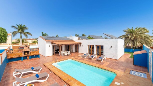 Un espace piscine aménagé sur le toit, avec des chaises longues, un barbecue et un coin salon abrité.