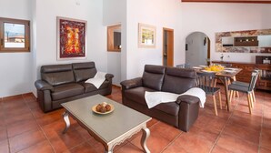 Un salon avec deux canapés en cuir, une table basse et un coin repas avec une table dressée pour deux personnes.