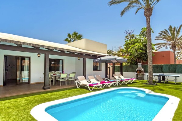 Ein modernes Haus mit Schwimmbad, Außenbereich zum Sitzen und Grillplatz.