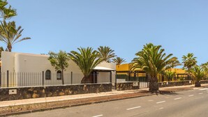 Eine Straße mit einer Steinmauer, Palmen und Gebäuden mit einer gelben Fassade.