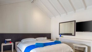 Ein Hotelzimmer mit Bett, Nachttisch, Spiegel und Fernseher.