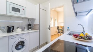Een kleine keuken met een magnetron, koffiezetapparaat en een wasmachine.
